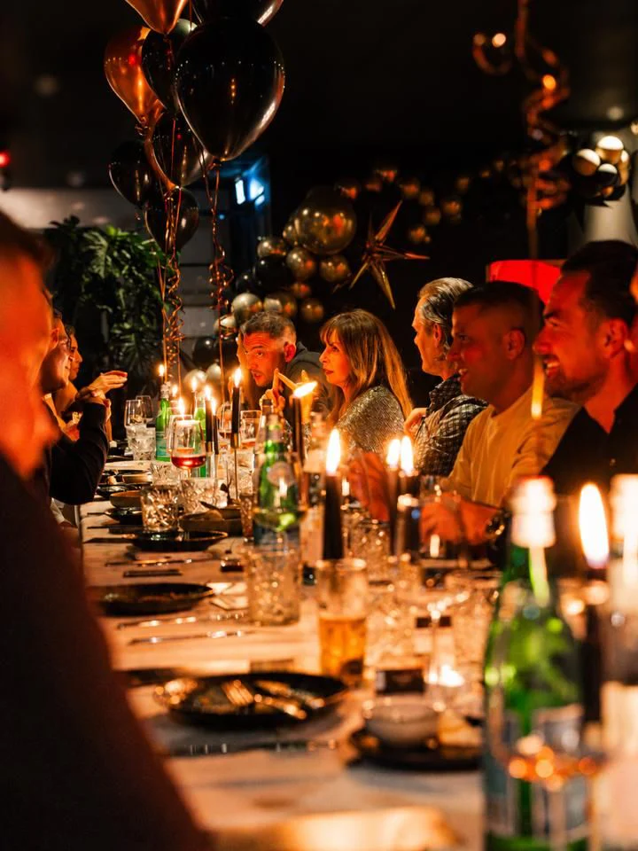 Een lange tafel met gasten bij kaarslicht bij CARBŌ